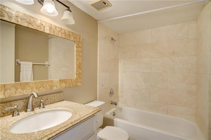 Full bathroom featuring tiled shower / bath, vanity, and toilet