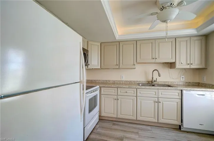 Kitchen featuring ceiling fan, light hardwood / wood-style floors, white appliances, a raised ceiling, and sink
