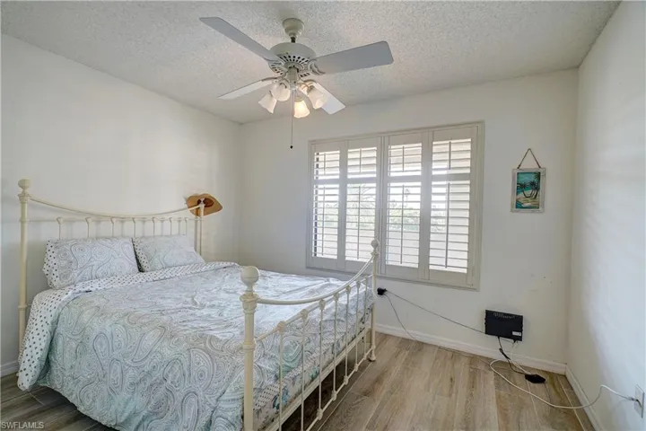 Bedroom featuring ceiling fan, a textured ceiling, and wood-type flooring