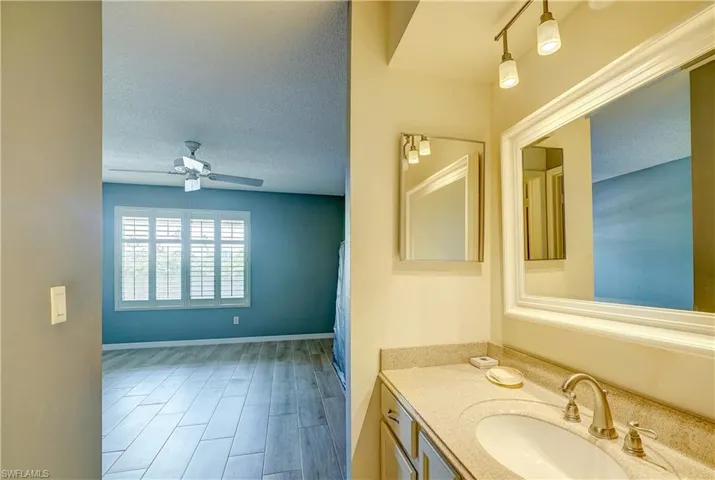 Bathroom with ceiling fan, a textured ceiling, oversized vanity, and rail lighting