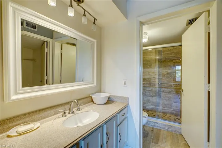 Bathroom with a shower with shower door, vanity, and toilet