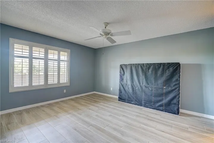 Unfurnished room featuring light hardwood / wood-style floors, a textured ceiling, and ceiling fan