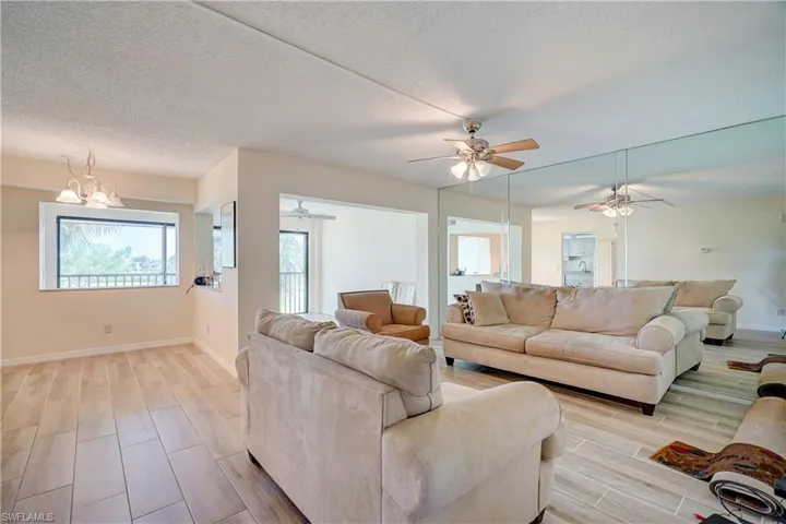 Living room featuring a textured ceiling, light hardwood / wood-style flooring, and ceiling fan with notable chandelier