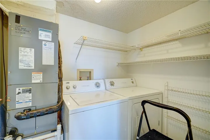 Clothes washing area with heating utilities, washing machine and clothes dryer, a textured ceiling, and hookup for a washing machine