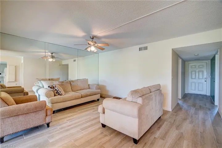 Living room with light hardwood / wood-style floors, ceiling fan, and a textured ceiling