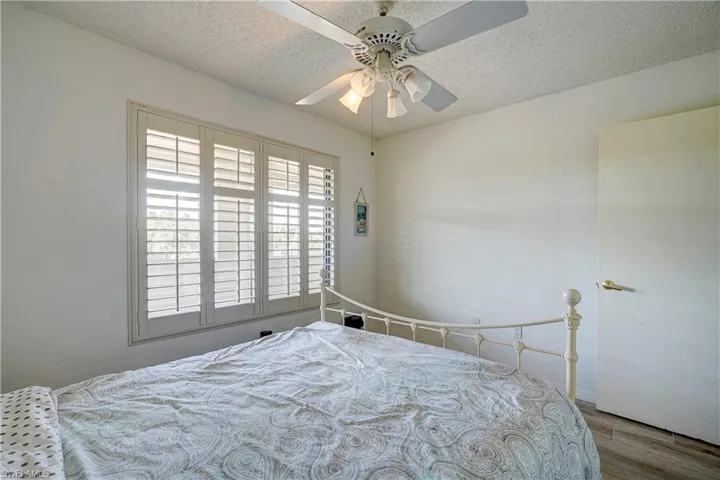 Bedroom with hardwood / wood-style floors, ceiling fan, and a textured ceiling