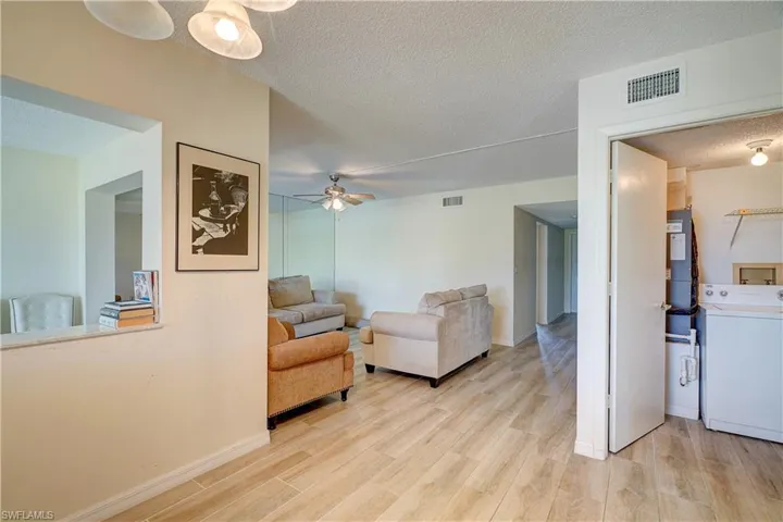 Living room featuring ceiling fan, light hardwood / wood-style floors, a textured ceiling, and washer / clothes dryer