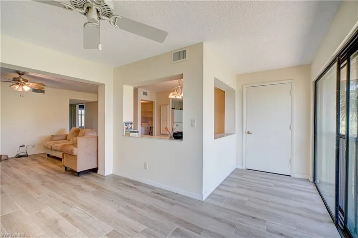 Empty room with ceiling fan, light hardwood / wood-style floors, a textured ceiling, and washer / dryer