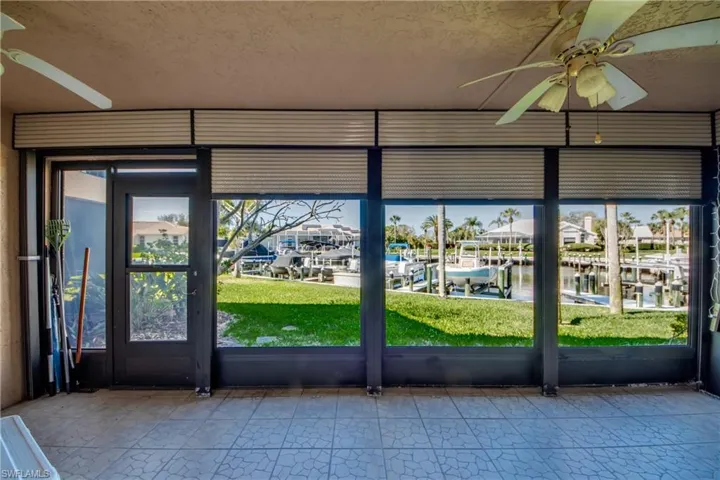 Unfurnished sunroom with a ceiling fan, plenty of natural light, and a residential view