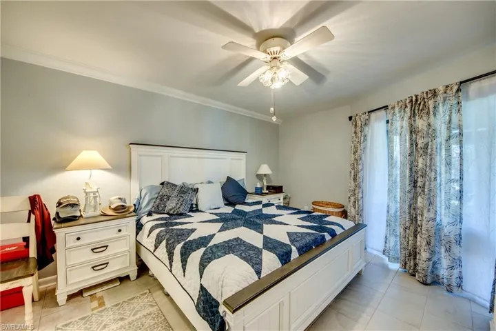 Bedroom with ceiling fan, ornamental molding, and light tile patterned floors