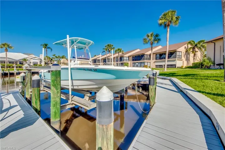Dock area featuring a water view, boat lift, and a yard