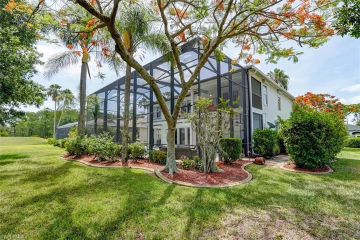 View of side of home featuring glass enclosure and a yard