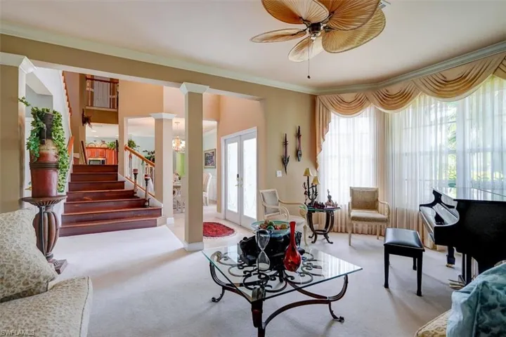 Living room with ornamental molding, french doors, carpet flooring, and decorative columns