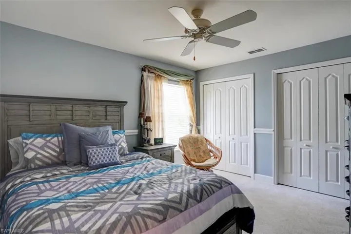Guest Bedroom with two closets, ceiling fan, and light colored carpet