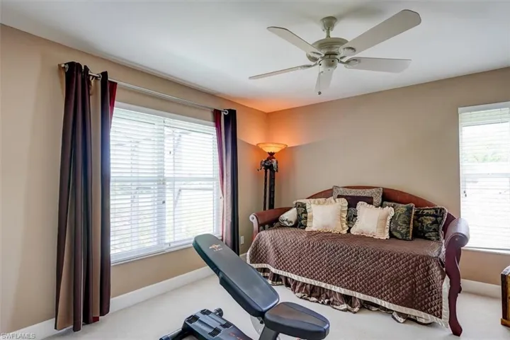 Carpeted Guest bedroom featuring ceiling fan and multiple windows