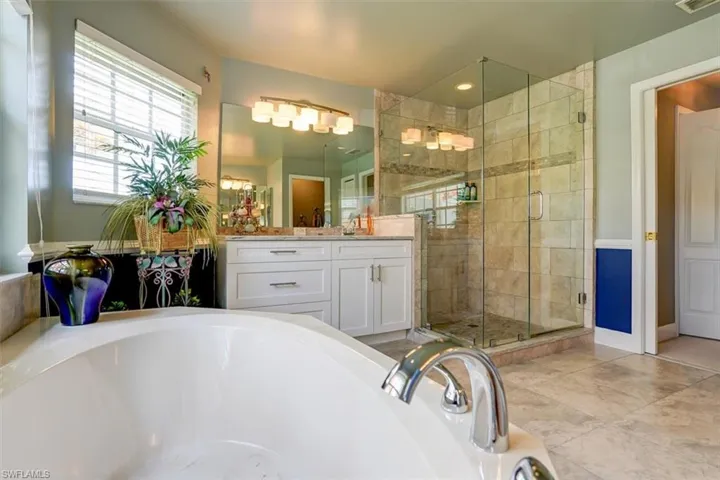 Bathroom featuring tile floors, independent shower and bath, and vanity