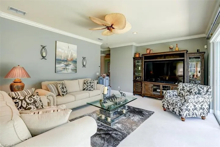 Great room with ceiling fan, ornamental molding, and carpet floors