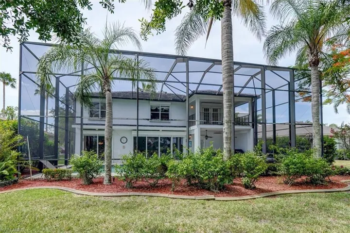 Rear view of property with a lawn and a lanai