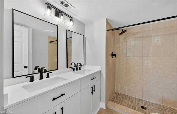 Full bathroom with double vanity and a shower stall