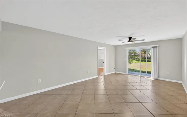 Empty room with a ceiling fan, light tile patterned floors, and a textured ceiling