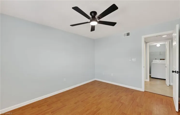 Unfurnished bedroom featuring washer / clothes dryer, light wood-style floors, and a ceiling fan