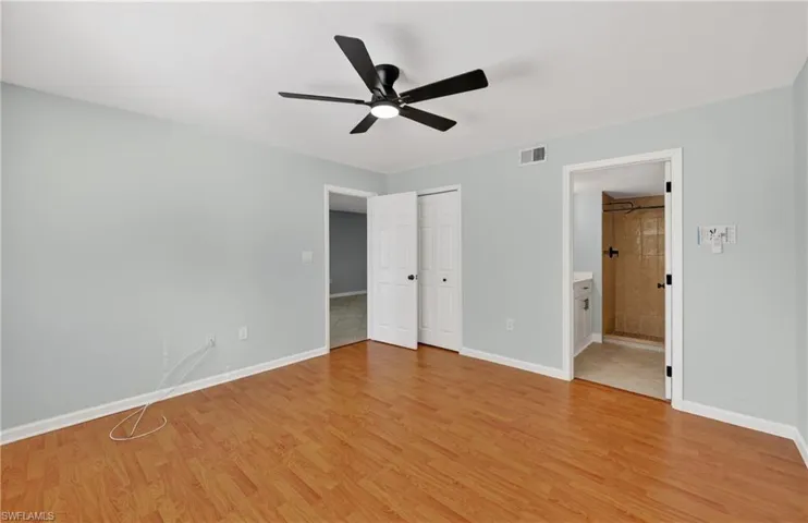Unfurnished bedroom featuring light wood finished floors, a ceiling fan, a closet, and ensuite bath