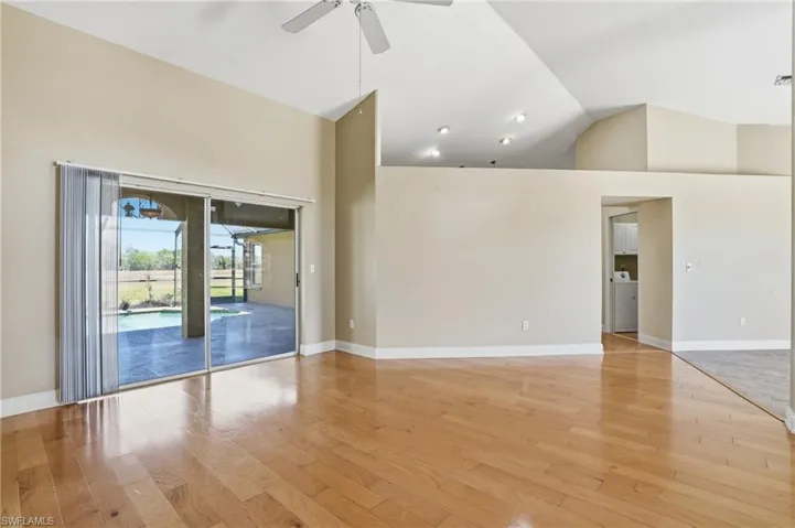 Empty room with light wood-style floors, ceiling fan, lofted ceiling, and washer / dryer