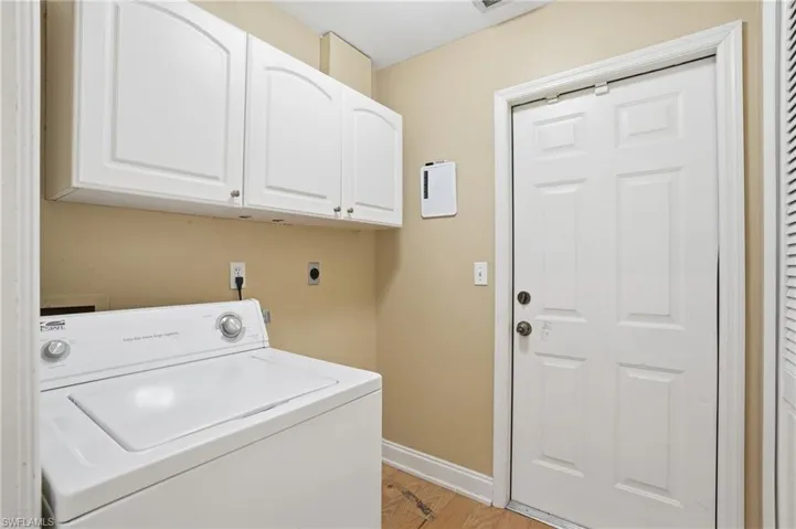 Laundry area with washer / clothes dryer, light wood-style floors, and cabinet space