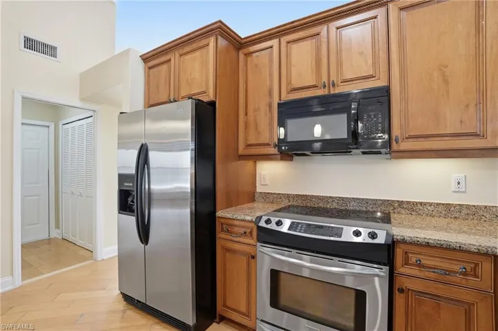 Kitchen featuring stainless steel appliances, light stone countertops, wood finish cabinetry, and light wood finished floors