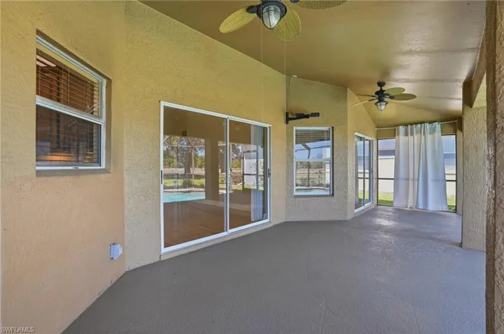 Unfurnished sunroom with a ceiling fan, a patio area, and lofted ceiling