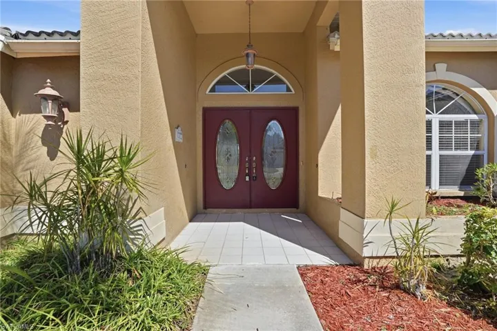 Entrance to property featuring stucco siding, a tiled roof, and french doors