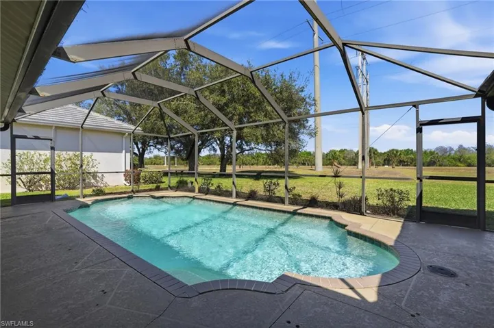 Swimming pool featuring a sunroom, glass enclosure, a patio area, and a lawn