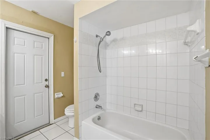 Bathroom featuring washtub / shower combination and tile patterned flooring