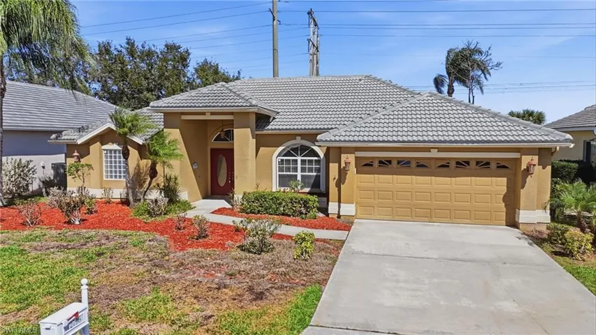 View of front of home with stucco siding, a tiled roof, a garage, and driveway