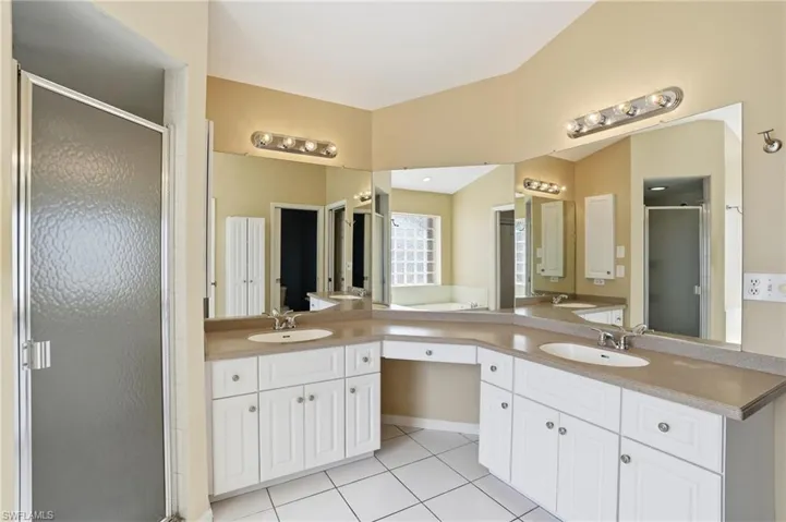 Full bath with a stall shower, double vanity, and light tile patterned floors