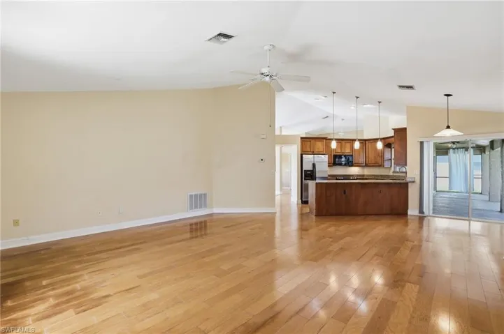 Unfurnished living room with ceiling fan, light wood-style flooring, and vaulted ceiling