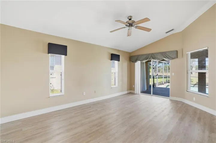 Spare room featuring ceiling fan, light wood-style floors, vaulted ceiling, and healthy amount of natural light