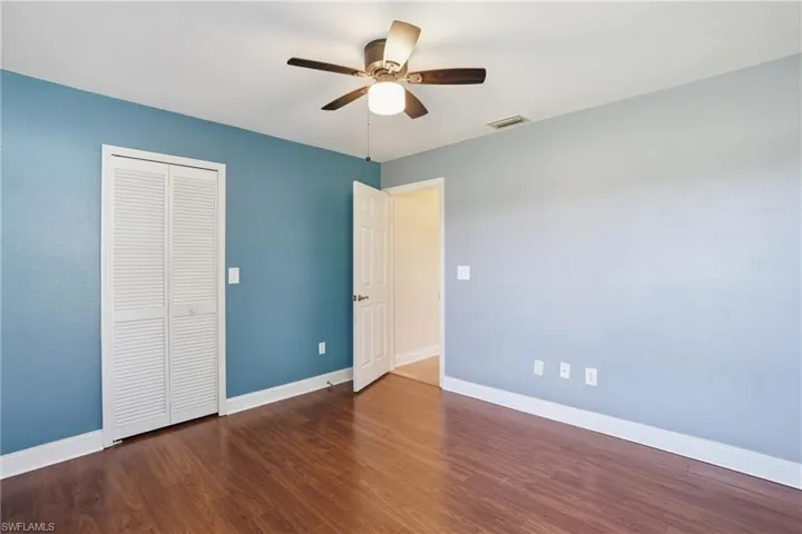 Unfurnished bedroom featuring a closet, dark wood-style flooring, and a ceiling fan