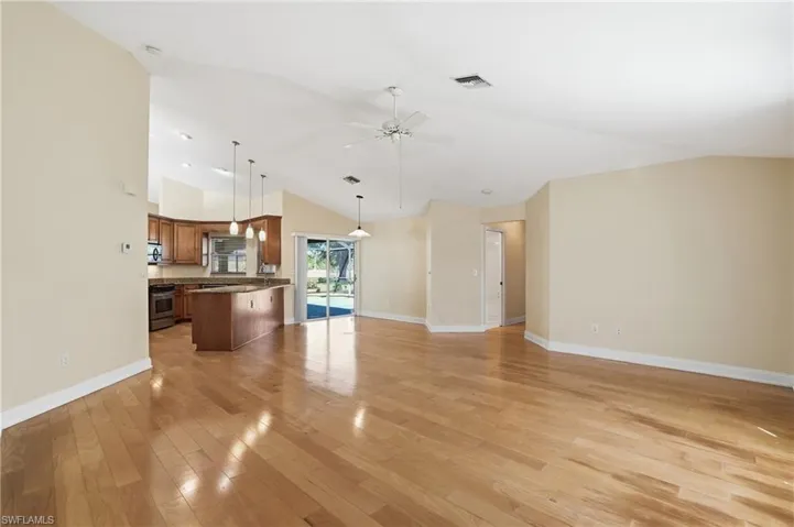 Unfurnished living room featuring light wood-style flooring, a ceiling fan, and vaulted ceiling