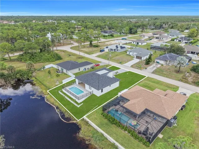 Modern residence with a private pool, an expansive green lawn, and waterfront access, situated in a suburban setting