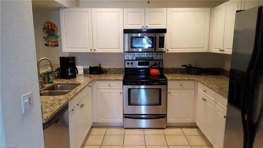 Kitchen featuring appliances with stainless steel finishes, a sink, and white cabinets