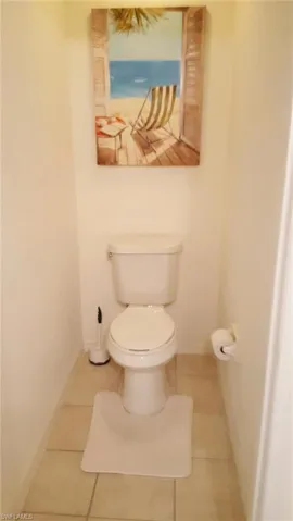 Bathroom with toilet, tile patterned floors, and baseboards
