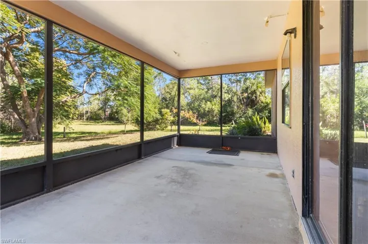 Unfurnished sunroom featuring plenty of natural light and view of wooded area