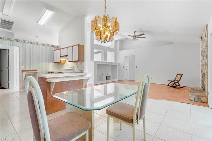 Dining area with a chandelier, a ceiling fan, high vaulted ceiling, and light tile patterned floors