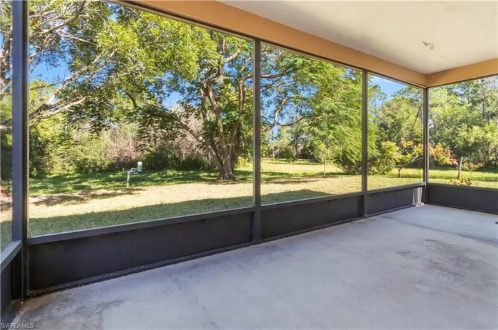Unfurnished sunroom featuring view of wooded area