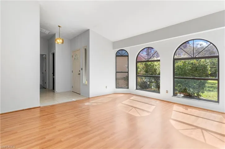 Spare room featuring light wood-type flooring, a chandelier, and lofted ceiling