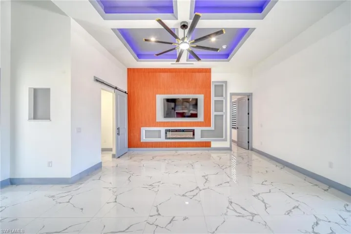 Unfurnished living room with marble finish floor, a barn door, baseboards, and coffered ceiling