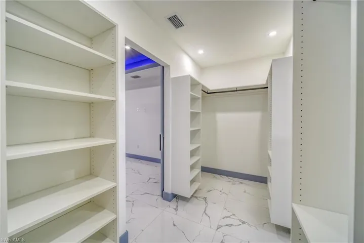 Spacious closet featuring marble finish floor and visible vents