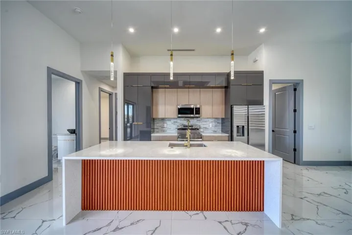 Kitchen with marble finish floor, appliances with stainless steel finishes, modern cabinets, and tasteful backsplash