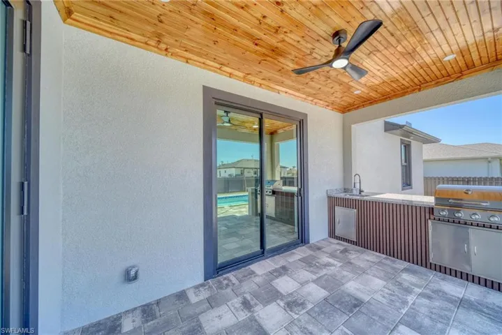 View of patio featuring area for grilling, a sink, ceiling fan, fence, and exterior kitchen